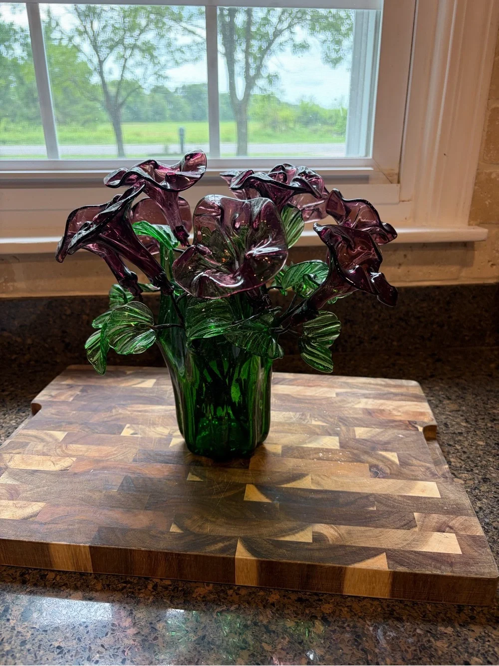 Vintage green swing glass vase with purple lily trumpet flowers.